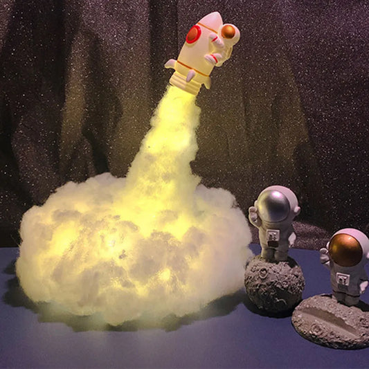 Lámpara LED 3D con forma de cohete y astronauta, nubes de colores.